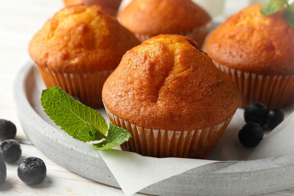 Tray with muffins on wooden background, close up