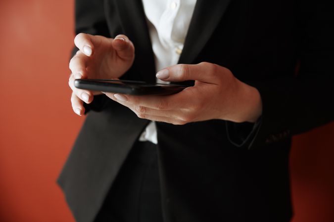 Young adult woman using smartphone next to the red wall
