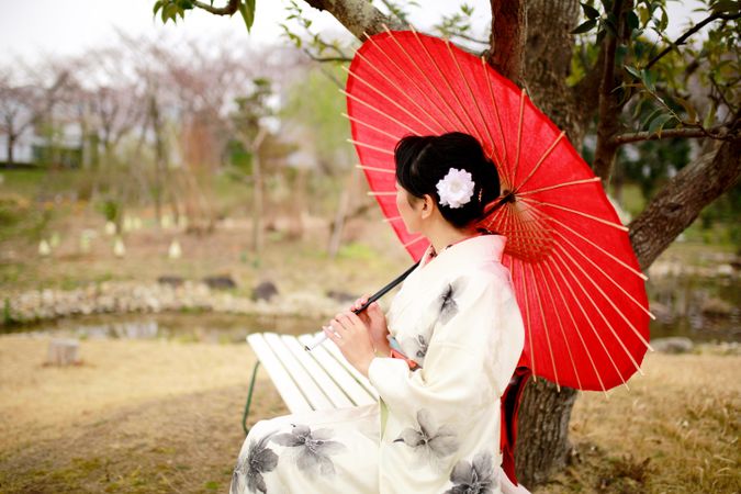 Woman in light and red floral kimono holding red umbrella