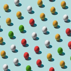 Pattern made of multi-colored eggs on pastel blue background