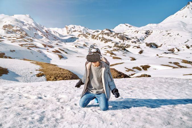 Anonymous boy in VR glasses in snowy mountains
