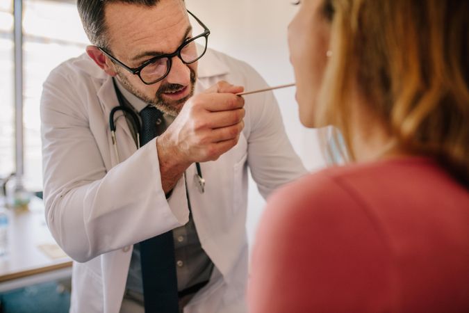 Male doctor checking for sore throat of woman patient