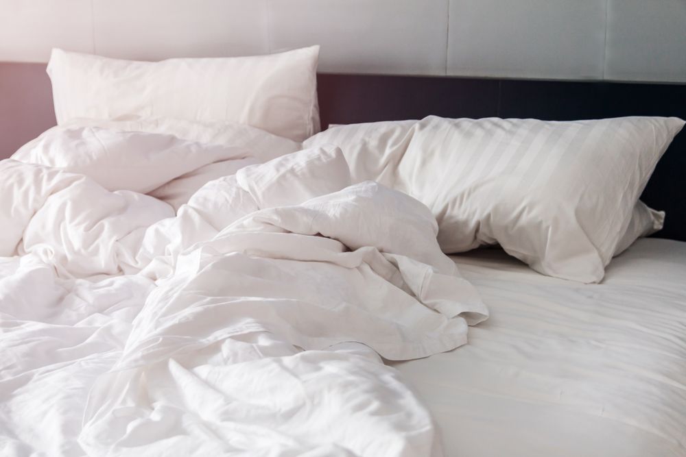 bed and pillows with wrinkle blanket in bedroom, from sleeping in a long night.