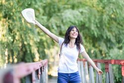 Smiling woman standing on foot bridge in forest