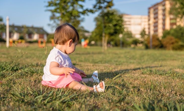 Happy baby girl playing sitting on a grass park