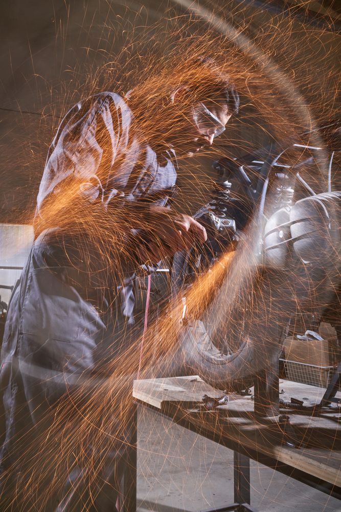 Man standing at workbench and repairing motorbike in workshop