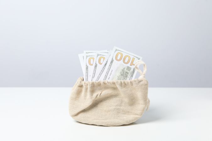 A bundle of 100 bucks in a bag on a light background.