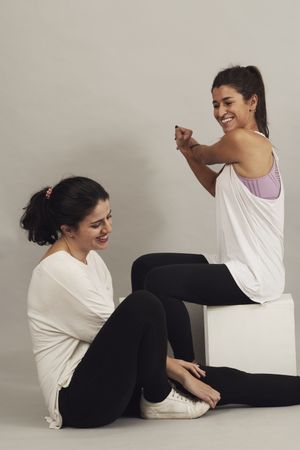 Happy young sportswomen resting after training in studio