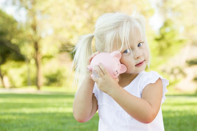 Little Girl Having Fun with Her Piggy Bank Outside