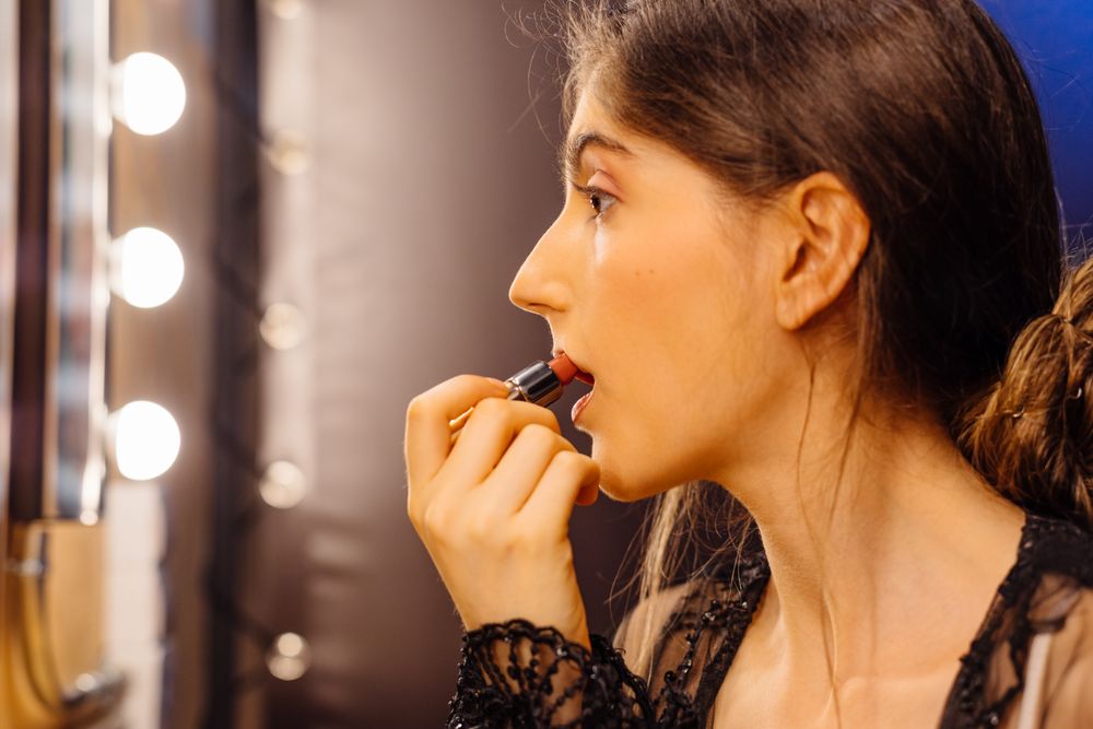 Glamorous female applying lipstick