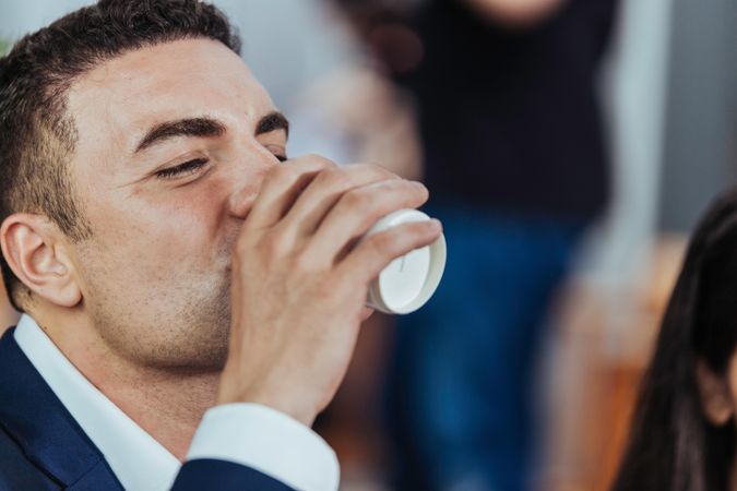 Man in suit drinking from to go cup