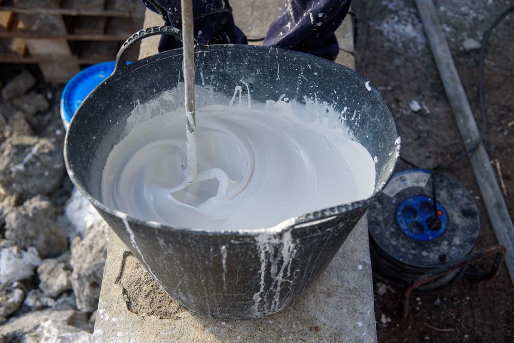 Worker mixing plaster in bucket