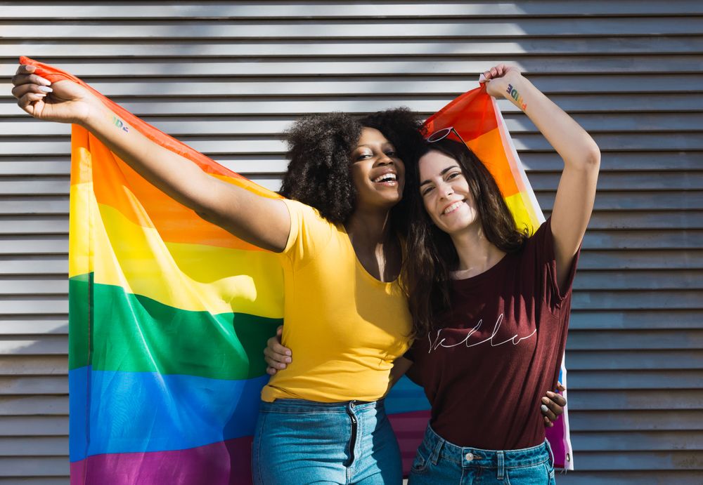 Women outside with LGBT flag on stairs
