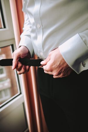 Man buttoning belt on pants