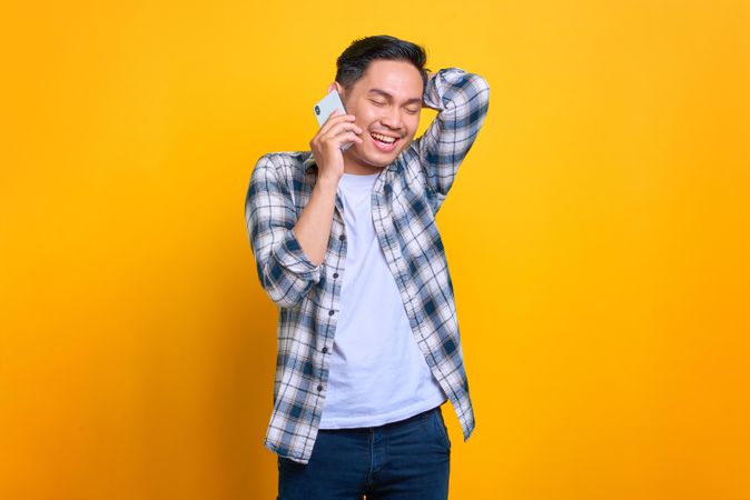 Asian male talking on mobile phone in studio shoot with eyes closed