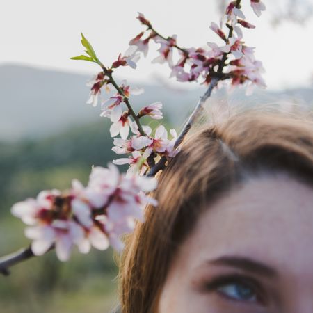 Young woman near tree twig with flowers