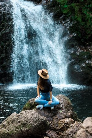 Smiling woman sitting near waterfall