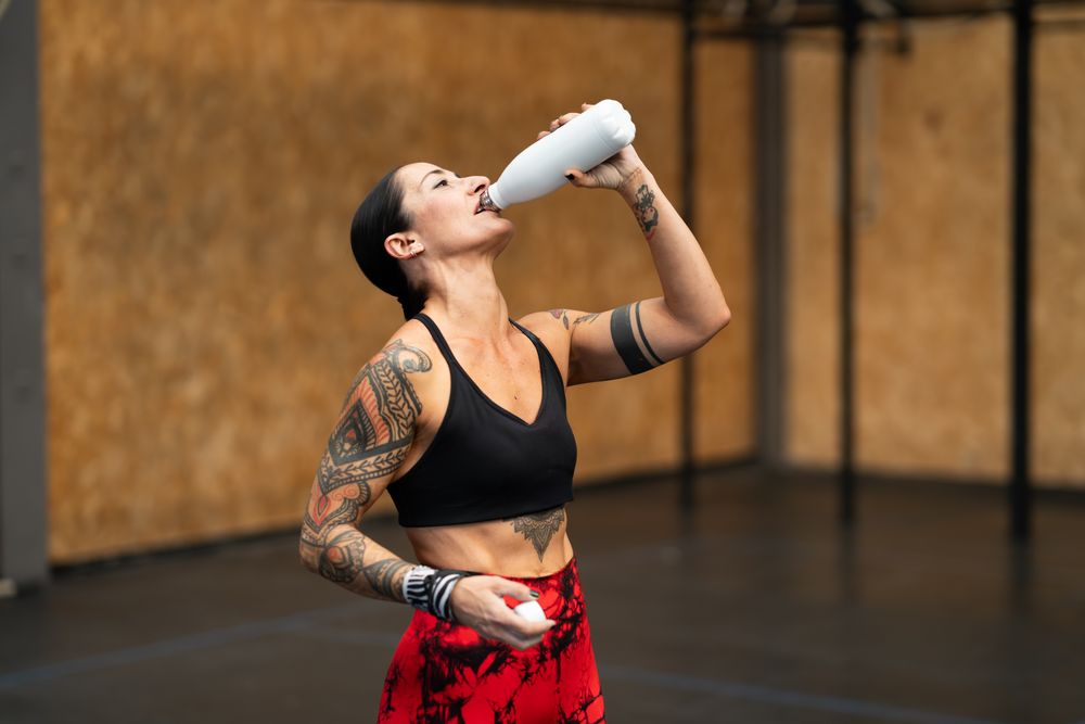 Tattooed fit woman drinking water