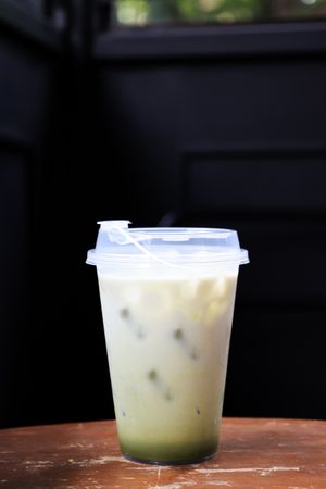 Iced Matcha Latte Green Tea with Milk Foam in a Plastic Takeaway Glass