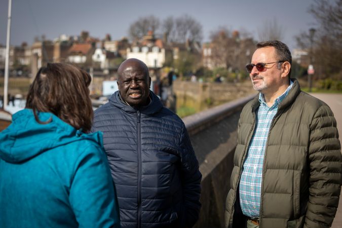 Two men and a woman having a conversation by the river