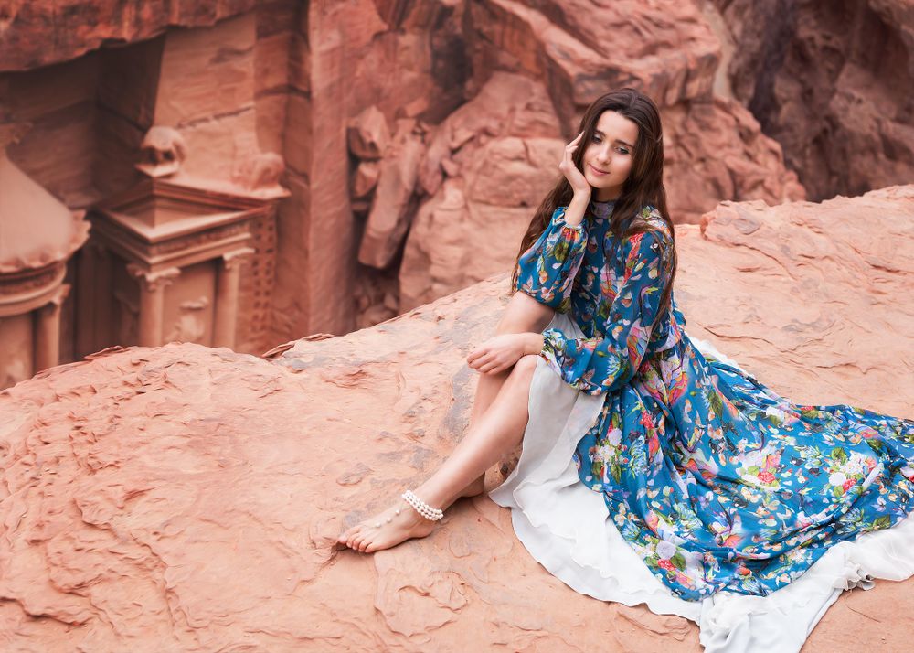 Woman in blue floral dress sitting on ground near Petra, Jordan 