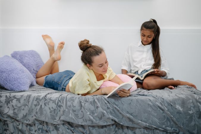 Teenage girls reading books on bed