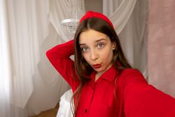 Teen girl posing for playful selfie in bright interior.