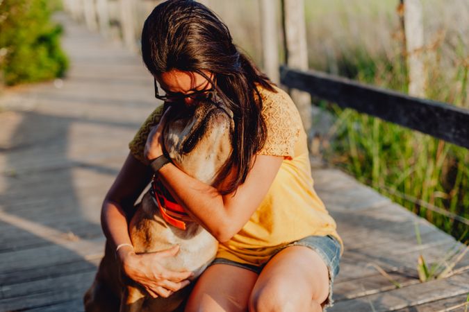 Happy adult woman hugging dog at countryside
