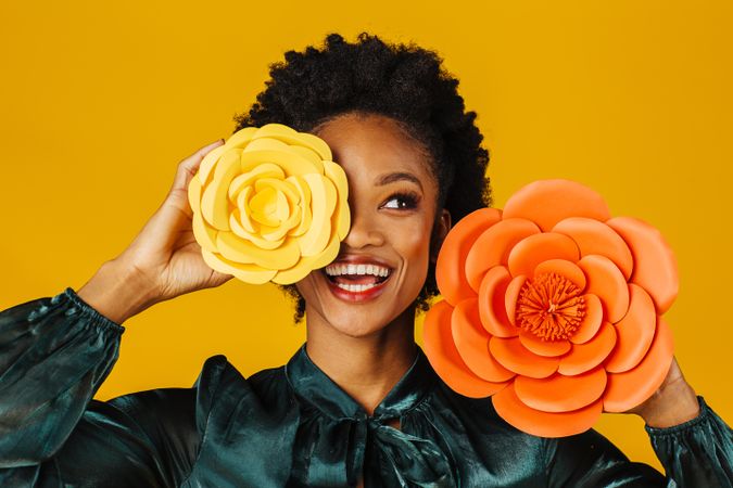 Beautiful Black woman holding two large flowers to her face