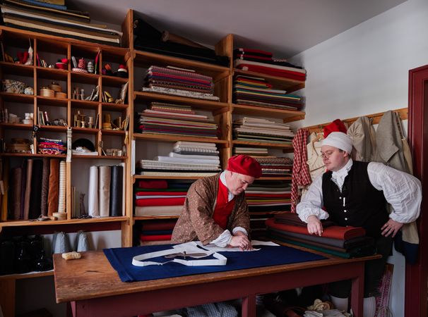Two men with fabrics tailoring a garment, Colonial Williamsburg, Virginia