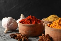 Side view of bowls of spices and garlic bulb, close up