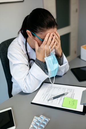 Female doctor with pandemic fatigue covering her face