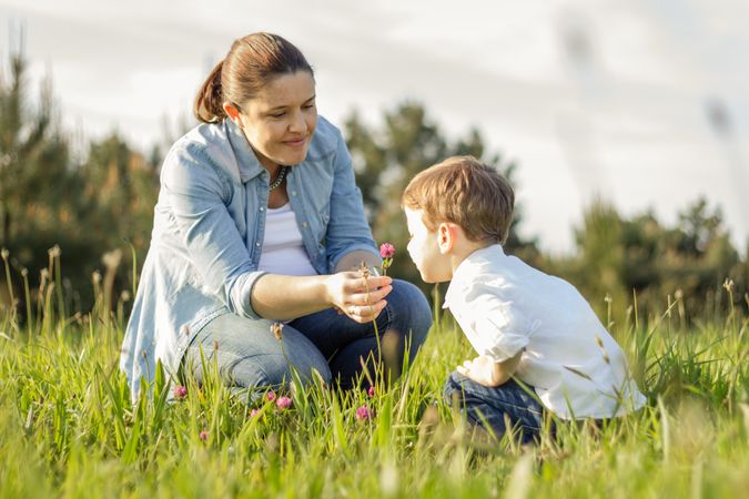 Pregnant mother and son picking flowers in a field