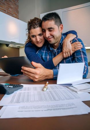 Happy couple as they organize bills together in their kitchen