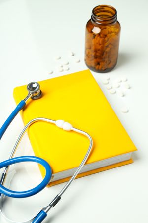 Medical literature - book and doctors accessories on light background