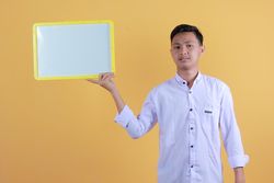 Portrait of a young man in yellow backdrop holding a blank note board
