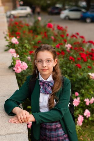 Girl in school uniform posing thoughtfully with smile.