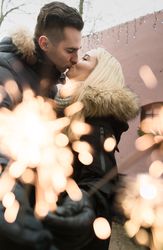 Smiling couple kissing on street with Bengal lights