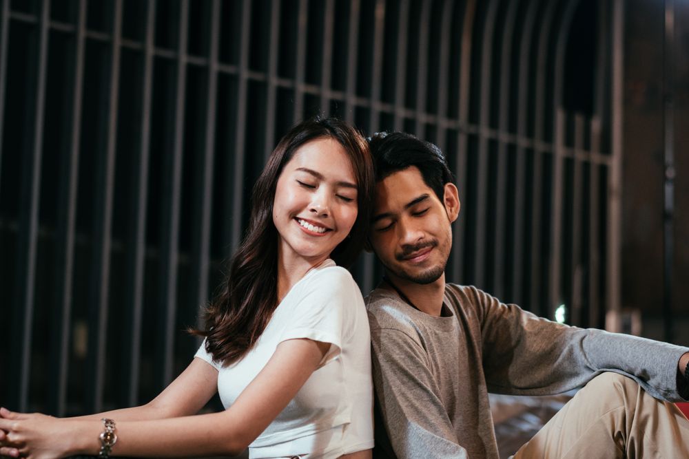 Man and woman sitting back to back on date night outside