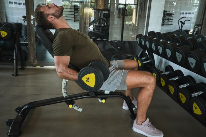 Strong man exercising with dumbbells in gym