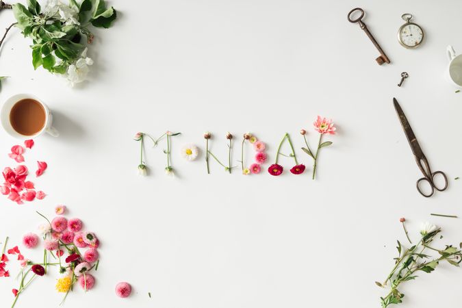 Word "MONDAY" made of flowers with various things on desk