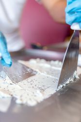 A worker is using spatulas to flatten a chocolate mix on a rolled ice cream machine