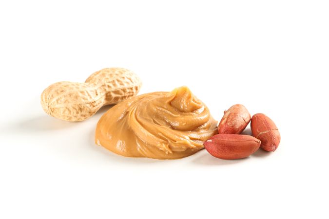 Creamy peanut butter and peanut isolated on light background. A traditional product of American cuisine