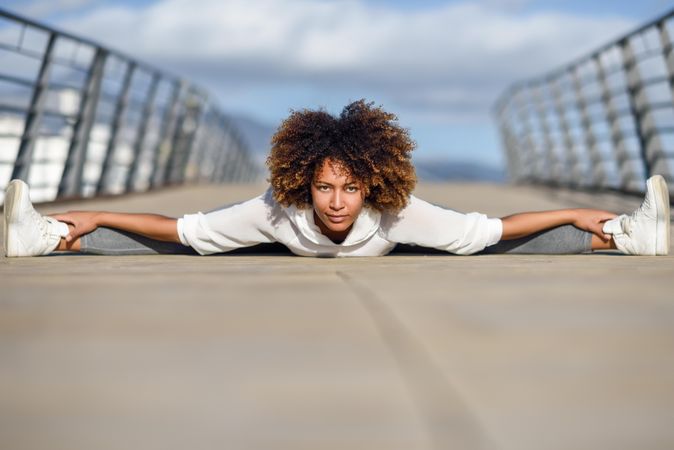 Woman leaning down touching her toes in splits on bridge with head resting on hands