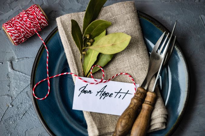Bon appetit note on napkin with bay leaf with string and knife and fork