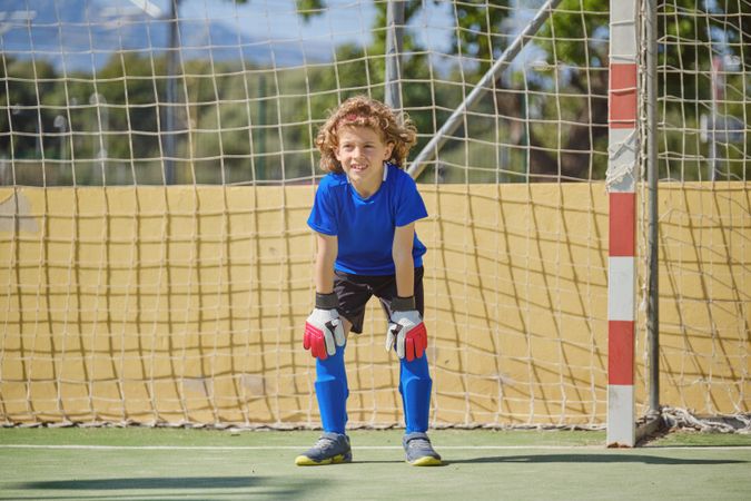 Happy boy standing at football goal