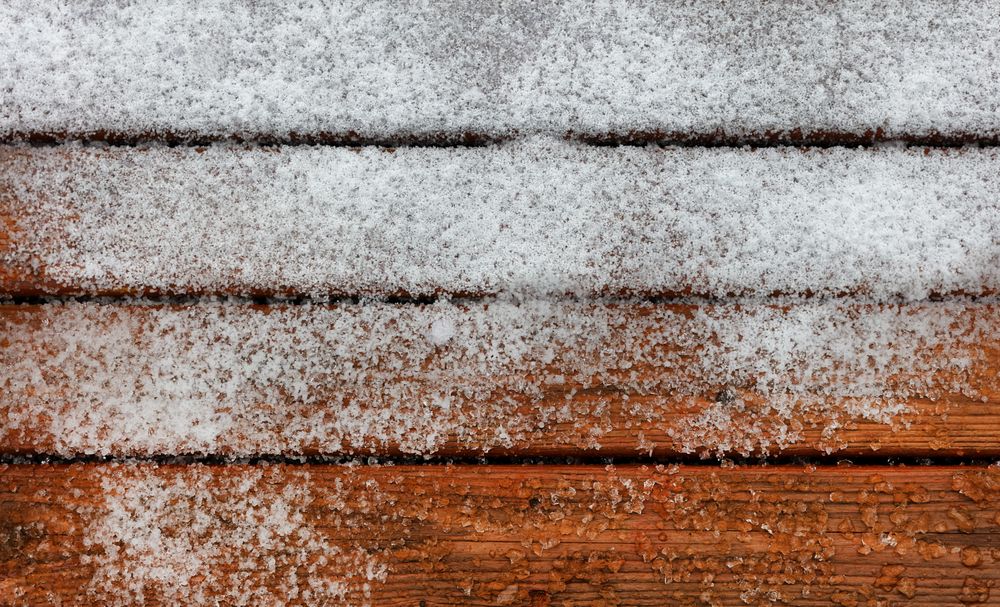 Outdoor deck wooden boards covered with snow and ice during winter