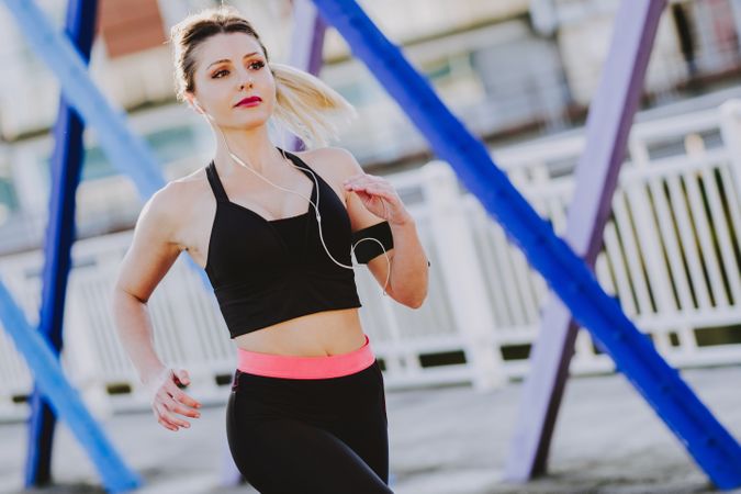 Woman with earphones running on street