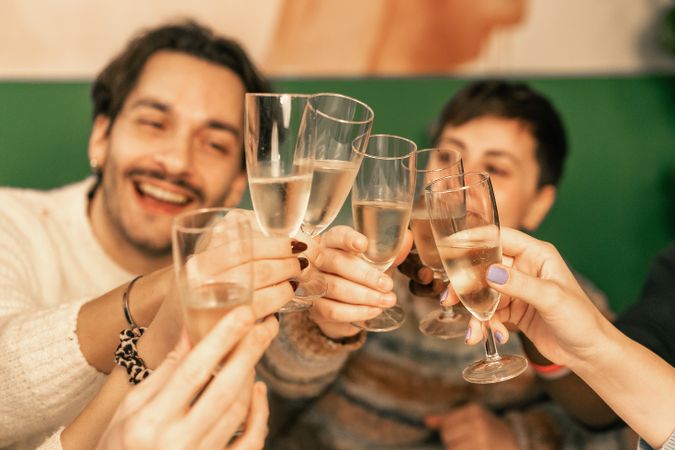 Group of happy friends laughing during a champagne toast at a Christmas party.