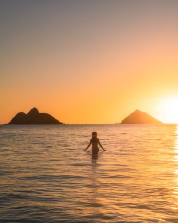Silhouette of woman in the ocean during sunset